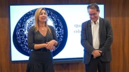 Augusto Cury, de terno escuro e óculos, sorrindo ao lado de uma palestrante durante evento