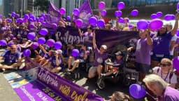 Grupo de pessoas com balões roxos participa de caminhada de conscientização sobre epilepsia