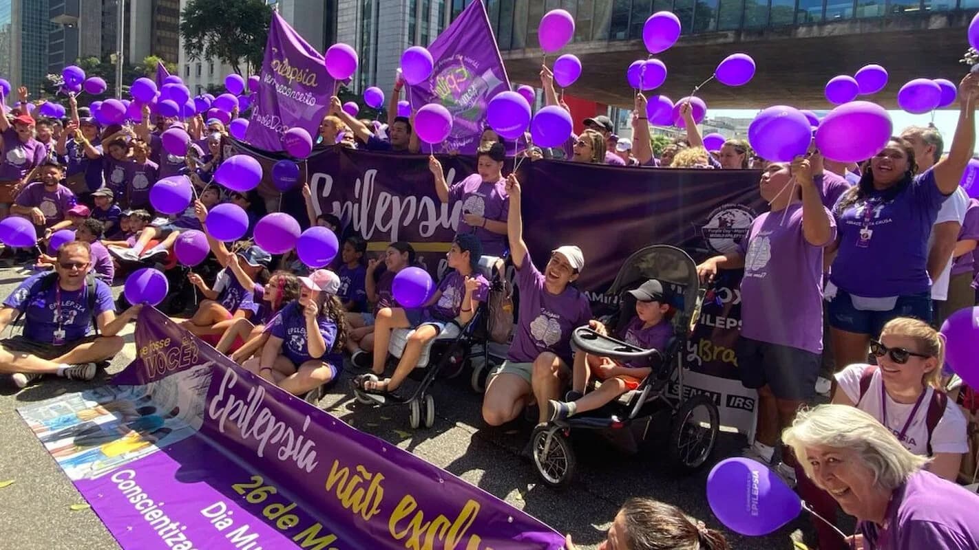 Grupo de pessoas com balões roxos participa de caminhada de conscientização sobre epilepsia