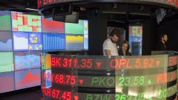 Painel de cotações em mercado financeiro, com operadores acompanhando preços de ações