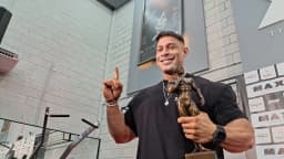 Ramon Dino sorri segurando o troféu do Mr. Olympia