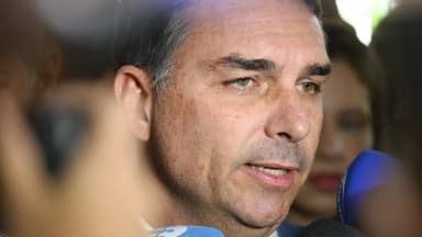 Senador Flávio Bolsonaro fala a jornalistas cercado de microfones em entrevista coletiva