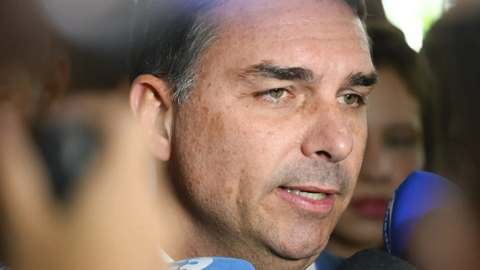 Senador Flávio Bolsonaro fala a jornalistas cercado de microfones em entrevista coletiva