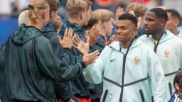 Kylian Mbappé sorri ao cumprimentar companheiros da seleção francesa antes de uma partida