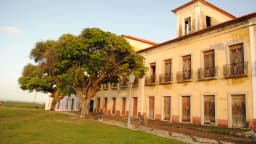 Fachada de casarão colonial amarelo com sacadas de ferro em Alcântara, Maranhão, ao lado de uma árvore frondosa