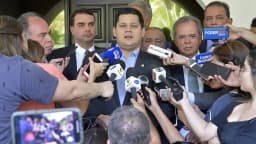 Flávio Bolsonaro cercado por microfones de emissoras de imprensa durante entrevista coletiva