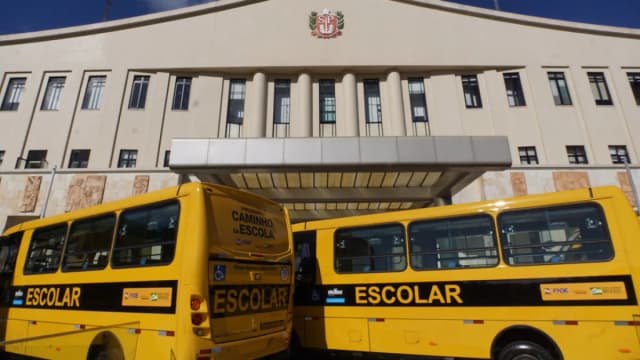 Ônibus escolares amarelos estacionados lado a lado em evento de entrega de veículos