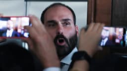 Eduardo Bolsonaro fala a repórteres cercado por celulares e câmeras