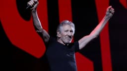 Roger Waters se apresenta ao vivo em show, com o punho erguido