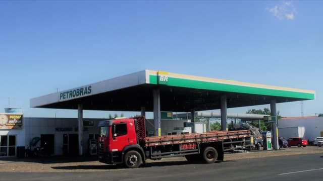 Foto de arquivo de um posto de combustíveis da bandeira Petrobras/BR visto de fora, com caminhão de carga vermelho estacionado em frente, em dia de céu azul
