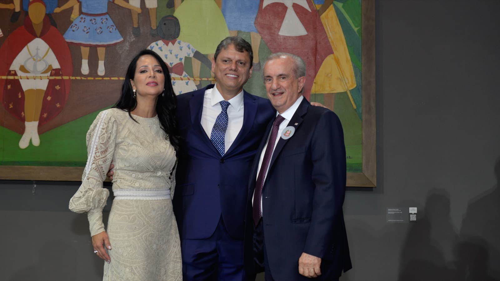 Tarcísio de Freitas sorri ao lado de duas pessoas em evento oficial, foto de arquivo