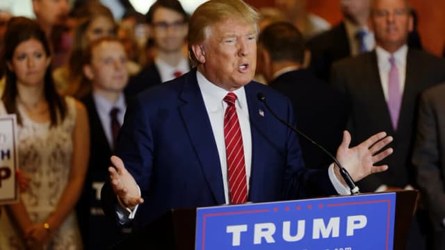 Donald Trump discursa em púlpito com bandeiras americanas ao fundo (foto de arquivo)