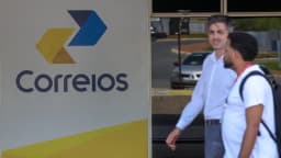 Fachada com logo dos Correios e pedestres passando em frente a uma agência, foto de arquivo