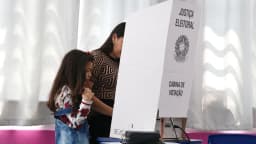 Eleitora acompanhada de criança em cabine de votação durante eleição (foto de arquivo)