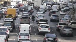 Motorista dirige um carro, com as mãos no volante, em cena de trânsito