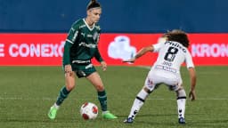 Jogadora do Palmeiras de uniforme verde disputa a bola com jogadora do Santos durante partida de futebol feminino