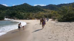 Pessoas caminham por praia de areia na região turística da Costa Verde fluminense, perto de Angra dos Reis