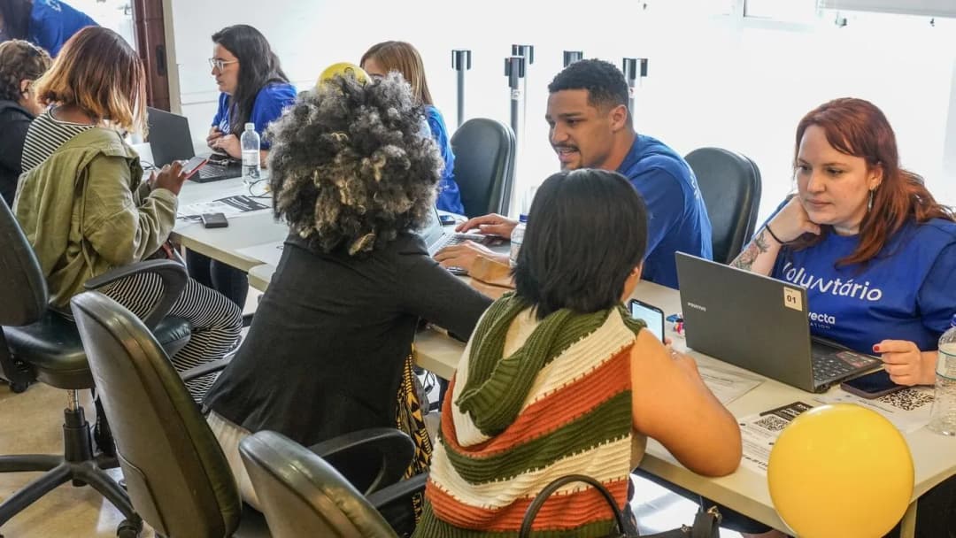 Pessoas reunidas ao redor de um laptop em ambiente de trabalho
