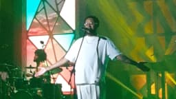 O rapper Emicida se apresenta em show com luzes coloridas no palco