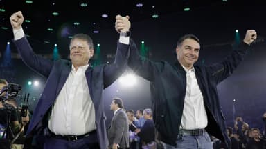 Tarcísio de Freitas e Flávio Bolsonaro de mãos dadas erguidas em evento de campanha