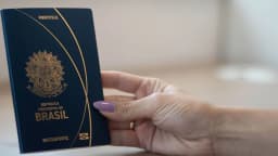 Mão segurando um passaporte brasileiro