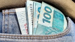 Notas de real de 100 reais no bolso de uma calça jeans