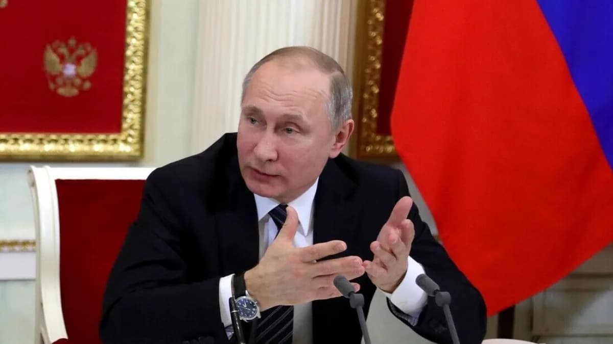 Vladimir Putin gesticula durante reunião no Kremlin, com bandeira da Rússia ao fundo
