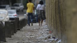Eleitores caminham por rua com material de campanha espalhado pelo chão em dia de eleição