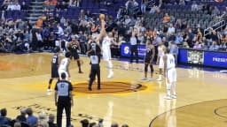 Jogadores de basquete em quadra da NBA durante partida, com arquibancada ao fundo