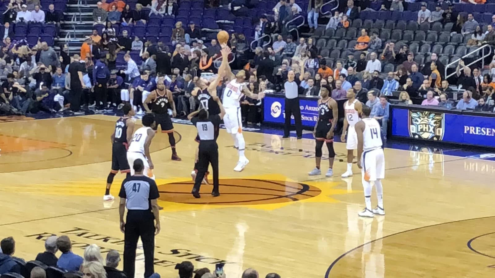 Jogadores de basquete em quadra da NBA durante partida, com arquibancada ao fundo