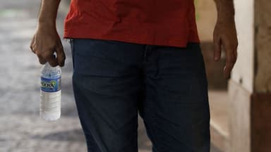 Pessoa segura garrafa de água gelada em dia de calor (foto de arquivo)