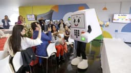 Pessoa fantasiada de urna eletrônica interage com público em evento do TSE contra desinformação