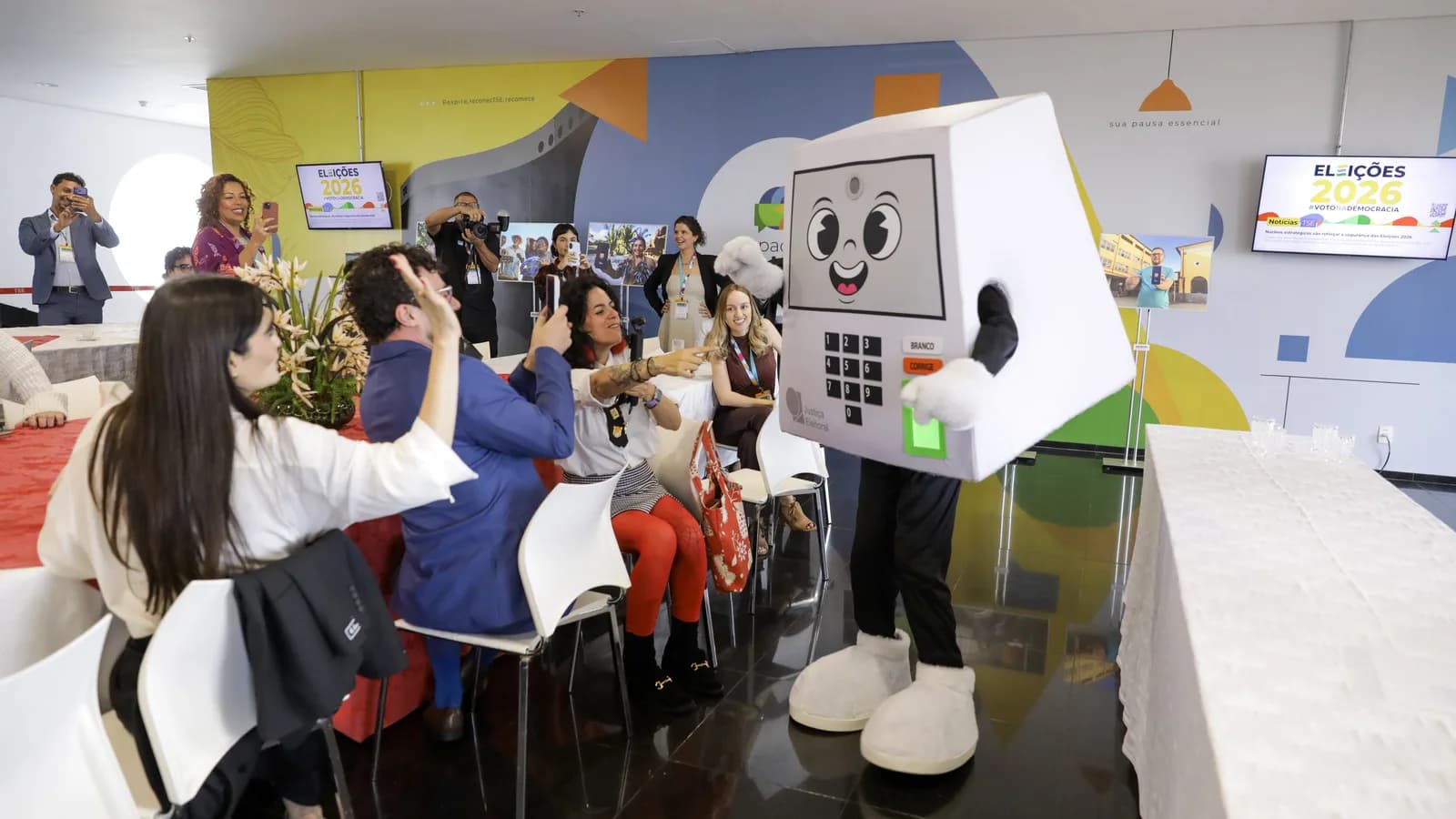 Pessoa fantasiada de urna eletrônica interage com público em evento do TSE contra desinformação