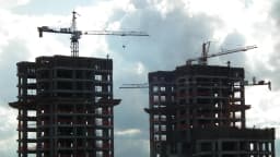 Prédios em construção com guindastes, representando o mercado imobiliário