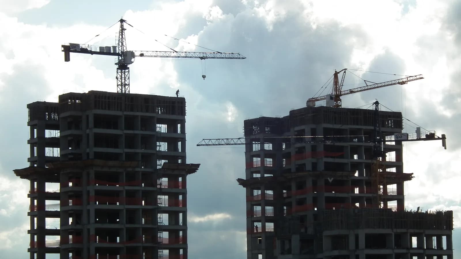 Prédios em construção com guindastes, representando o mercado imobiliário