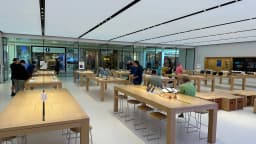 Clientes observam produtos em mesas de madeira dentro de uma loja da Apple