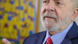 Presidente Luiz Inácio Lula da Silva gesticula durante entrevista, vestindo terno azul e gravata vermelha