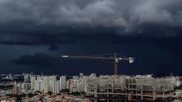 Céu com nuvens escuras de tempestade sobre área urbana, com guindaste de obra ao fundo