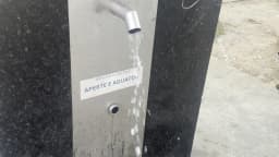 Água sai da bica do bebedouro do refúgio climático da Avenida Olegário Maciel, no Centro de Belo Horizonte, acima da placa "Aperte e aguarde"