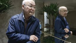 Dois homens idosos de origem coreana conversam em um ambiente interno em São Paulo