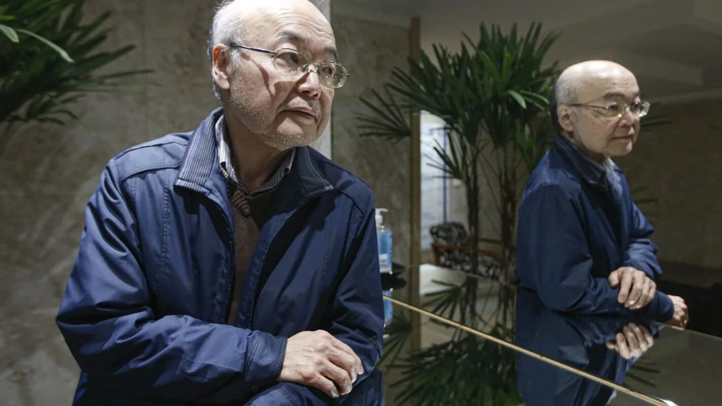 Dois homens idosos de origem coreana conversam em um ambiente interno em São Paulo