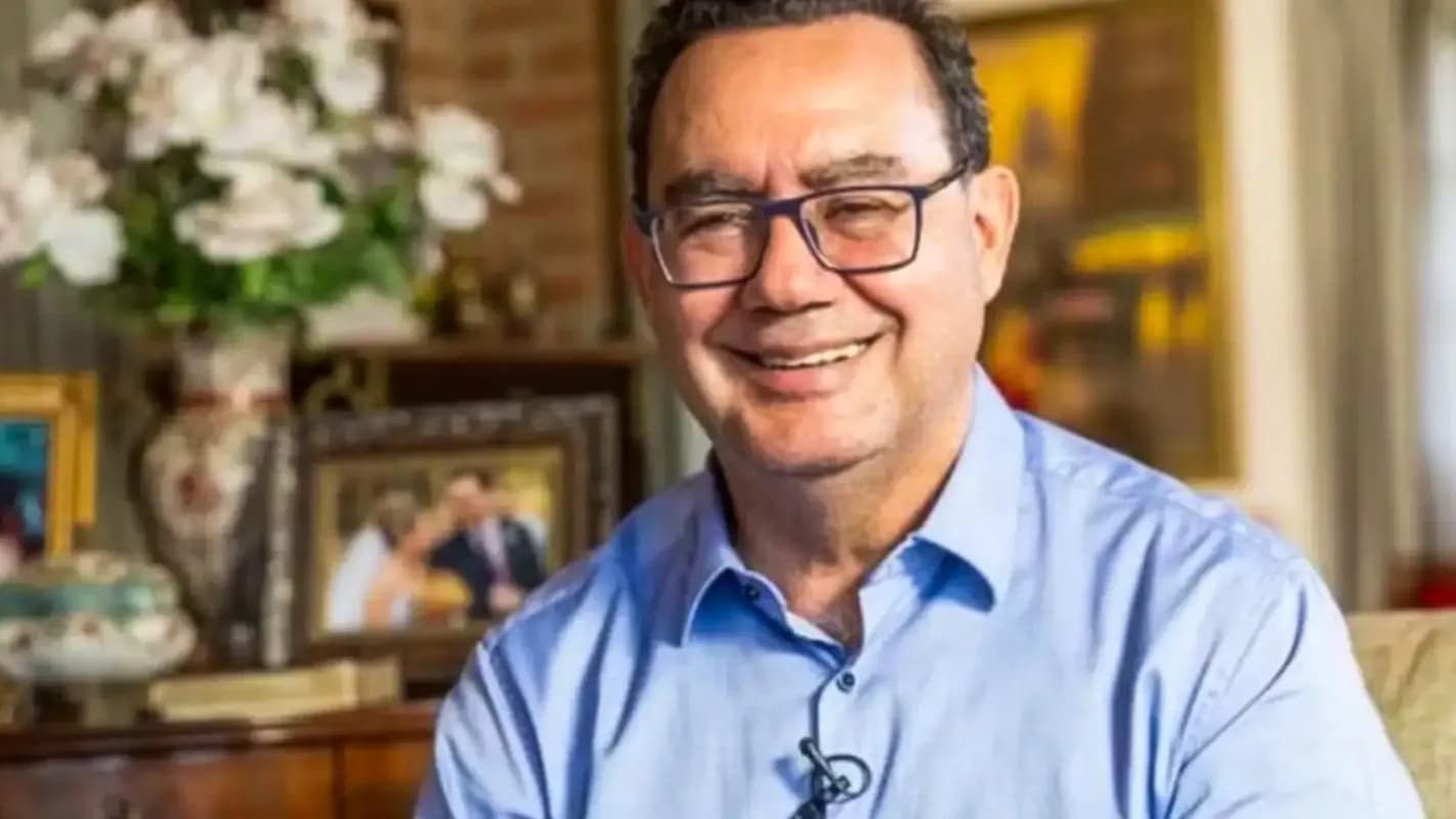 Augusto Cury, de óculos e camisa azul, sorri durante entrevista em casa