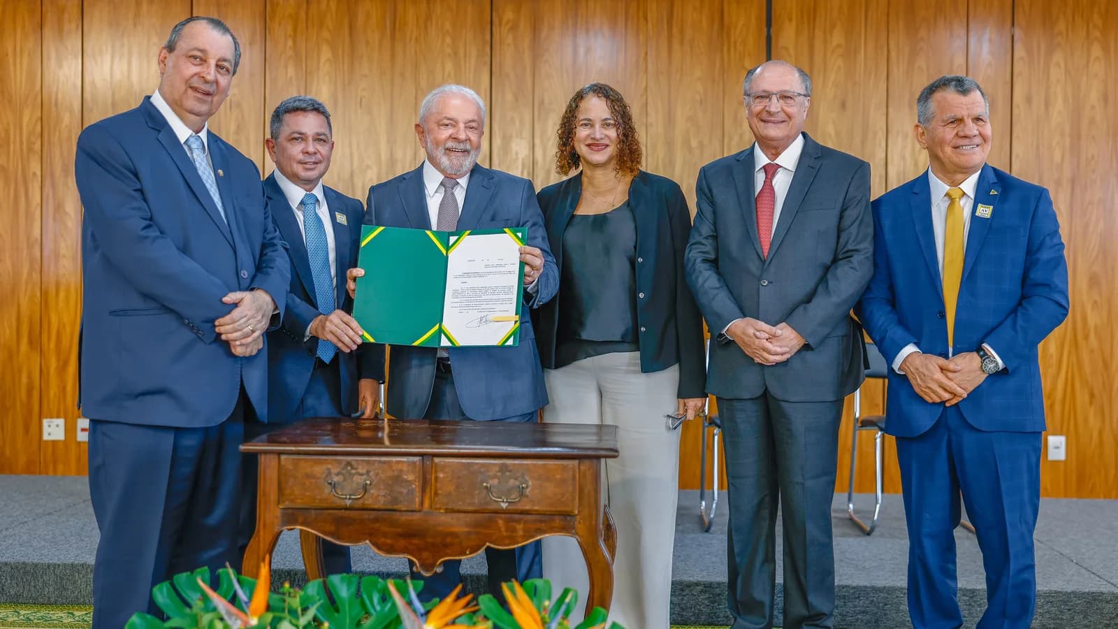 O presidente Luiz Inácio Lula da Silva sorri ao segurar pasta de decreto assinado, cercado de autoridades no Palácio do Planalto (foto de arquivo)
