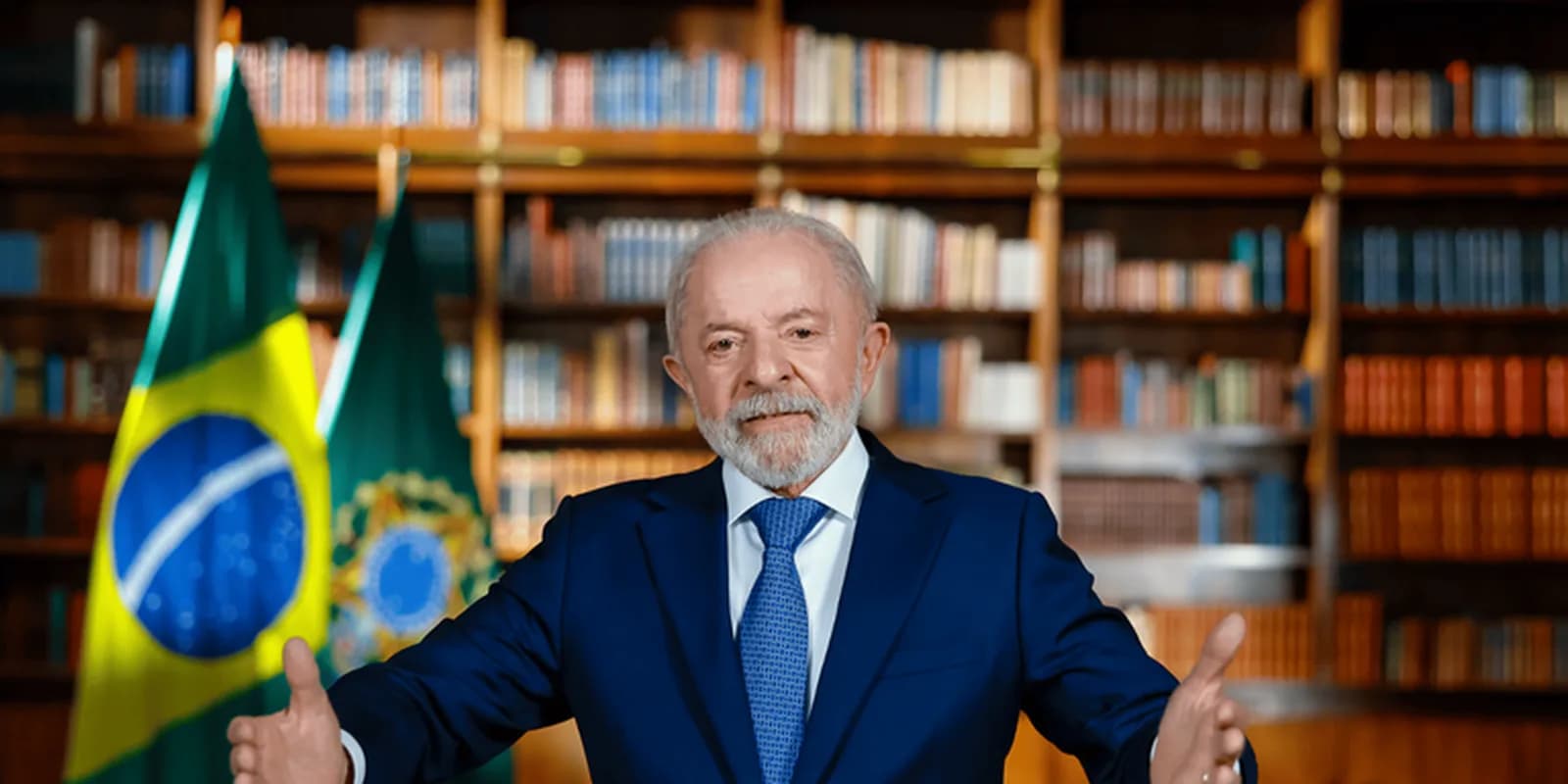 Presidente Lula durante pronunciamento em cadeia nacional, de terno azul, gesticulando diante de bandeiras do Brasil, em foto de arquivo