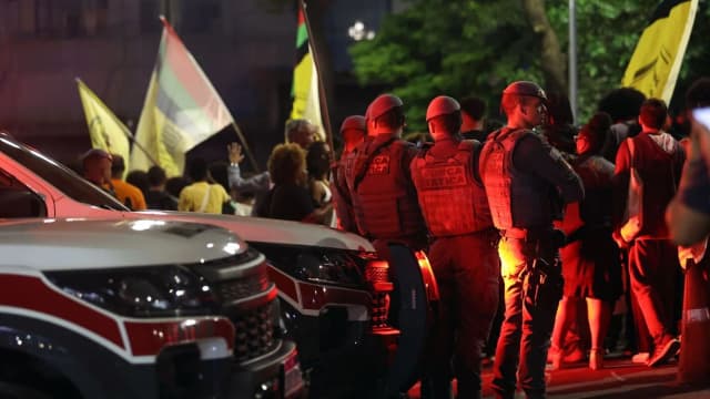 Policiais em operação ao lado de viaturas em via pública