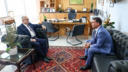 O senador Flávio Bolsonaro conversa com o ministro do STF Edson Fachin em gabinete, sentados em poltronas de couro