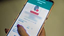 Mão segura celular com aplicativo eleitoral do TSE aberto na tela