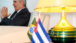 Embaixador de Cuba no Brasil, Victor Manuel Cairo Palomo, sentado em entrevista com bandeiras do Brasil e de Cuba ao fundo