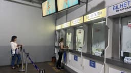 Passageiras em bilheteria de estação de trem com aviso "Aceitamos Pix"