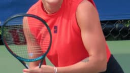 Aryna Sabalenka em ação durante treino, vestida de vermelho, raquete em punho
